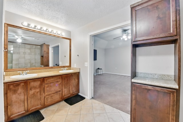 bathroom featuring a textured ceiling, ceiling fan, a sink, and tile patterned floors