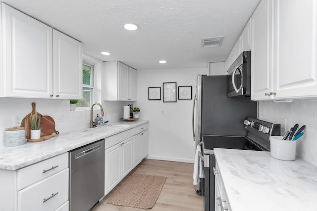kitchen with visible vents, light wood-type flooring, a sink, backsplash, and stainless steel appliances