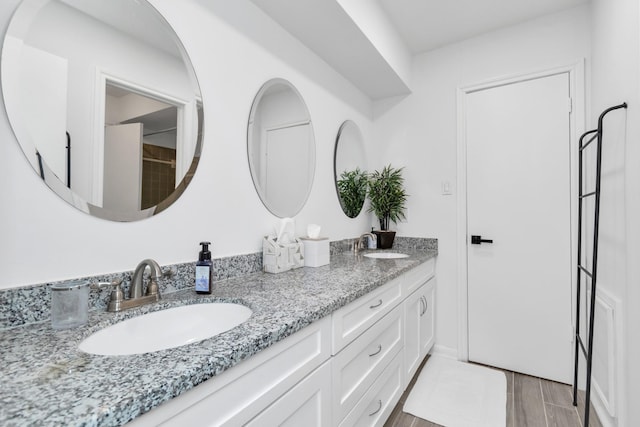 full bath featuring double vanity, a sink, and wood finished floors