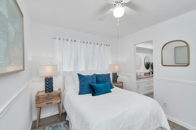 bedroom featuring baseboards, ensuite bath, wood finished floors, and ceiling fan