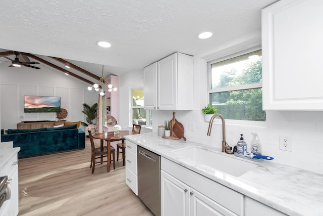 kitchen with stainless steel dishwasher, open floor plan, a textured ceiling, a sink, and light wood-style flooring