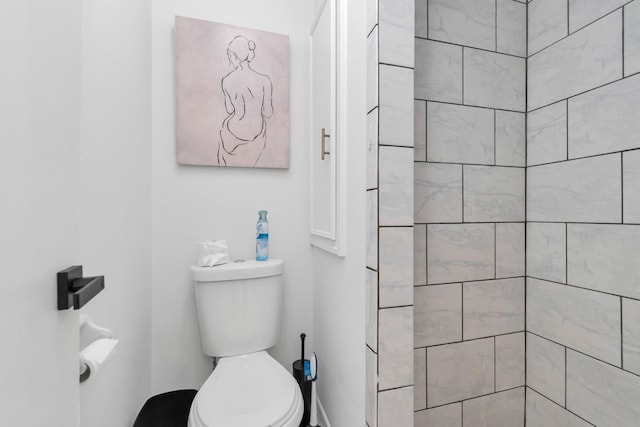 bathroom with a tile shower and toilet