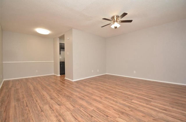 spare room with a ceiling fan, baseboards, and light wood finished floors