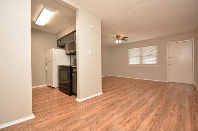 kitchen with black electric range oven, light wood-style floors, baseboards, ceiling fan, and stainless steel microwave
