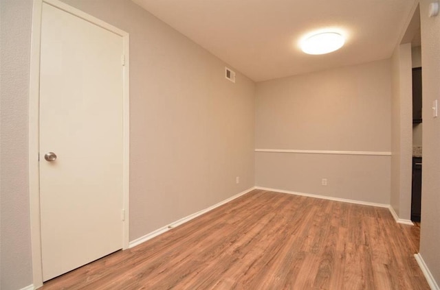 unfurnished room with baseboards, wood finished floors, and visible vents