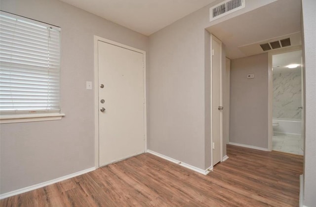 foyer entrance featuring visible vents, baseboards, and wood finished floors