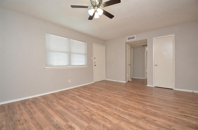 spare room featuring a ceiling fan, baseboards, visible vents, and wood finished floors