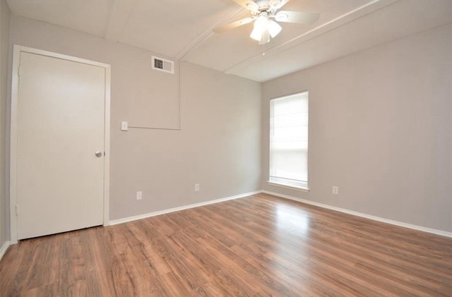 spare room featuring a ceiling fan, baseboards, visible vents, and wood finished floors