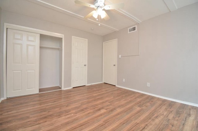 unfurnished bedroom featuring baseboards, a closet, wood finished floors, and visible vents