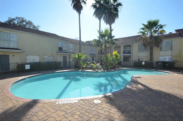 community pool with a patio and fence