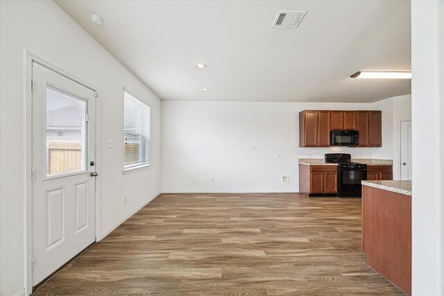 kitchen featuring visible vents, brown cabinets, light countertops, black appliances, and light wood finished floors