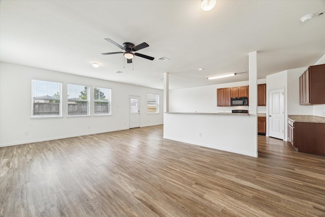 unfurnished living room featuring baseboards, a ceiling fan, wood finished floors, and visible vents