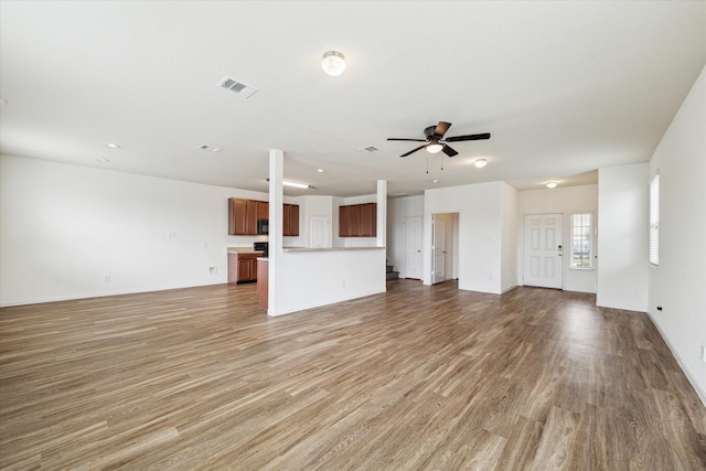 unfurnished living room with visible vents, a ceiling fan, light wood finished floors, and baseboards