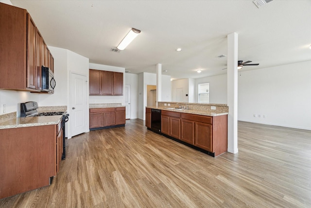 kitchen featuring ceiling fan, a sink, light wood finished floors, black dishwasher, and gas range