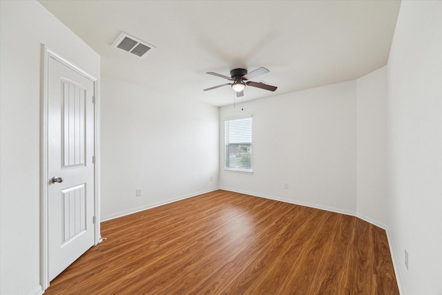 spare room featuring visible vents, a ceiling fan, baseboards, and wood finished floors