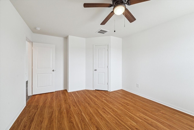 unfurnished bedroom with visible vents, baseboards, ceiling fan, and wood finished floors