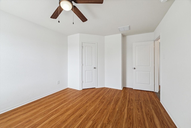 unfurnished bedroom featuring a ceiling fan, baseboards, visible vents, and wood finished floors