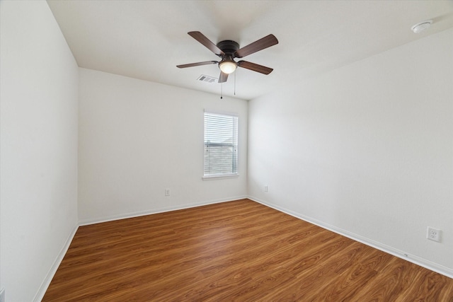 spare room with baseboards, a ceiling fan, wood finished floors, and visible vents