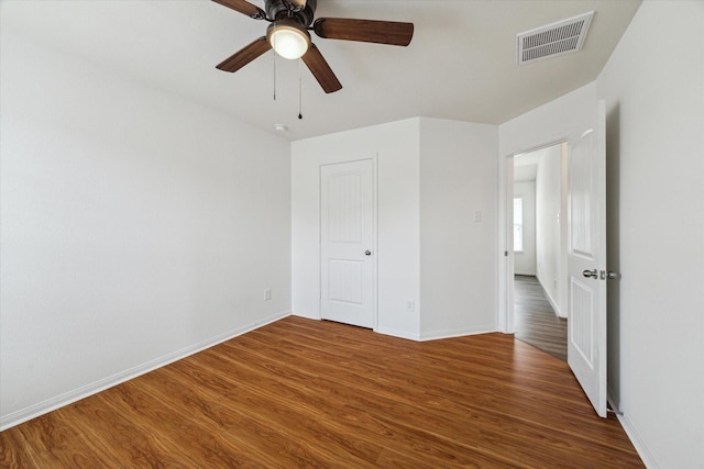unfurnished bedroom with baseboards, a ceiling fan, wood finished floors, and visible vents
