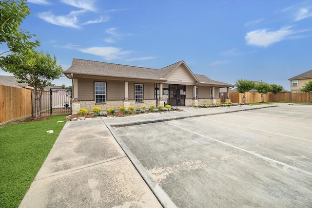 single story home with fence, a gate, uncovered parking, and stone siding