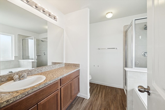 full bathroom with a stall shower, wood finished floors, vanity, baseboards, and toilet