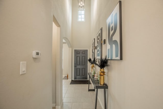 interior space with arched walkways, baseboards, light tile patterned floors, and a high ceiling