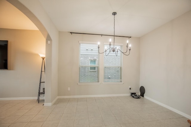unfurnished dining area with arched walkways, baseboards, a chandelier, and light tile patterned floors