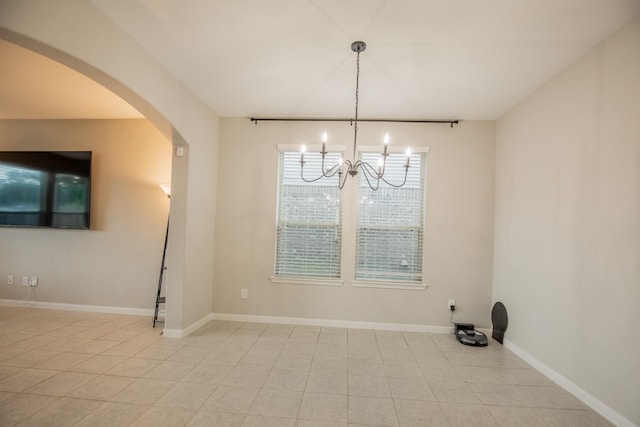 unfurnished dining area with an inviting chandelier, arched walkways, baseboards, and tile patterned floors