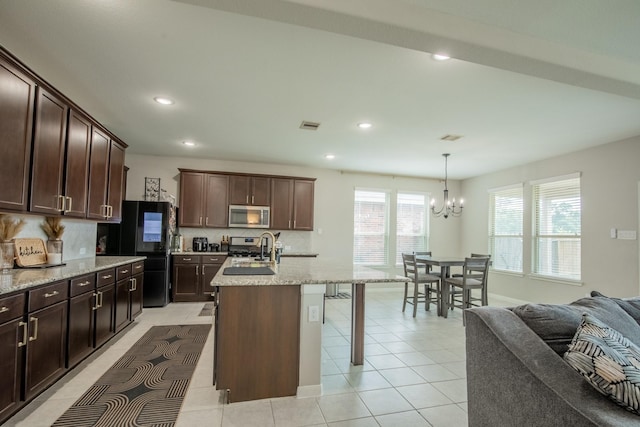 kitchen featuring decorative backsplash, dark brown cabinetry, a kitchen breakfast bar, a notable chandelier, and stainless steel appliances