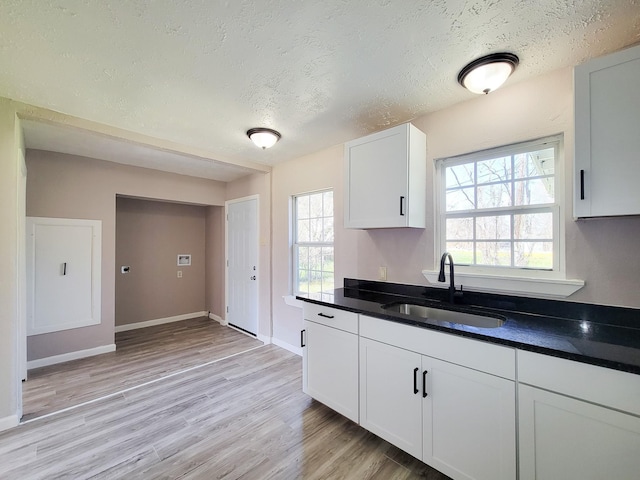 kitchen featuring a sink, dark countertops, light wood-type flooring, and a textured ceiling