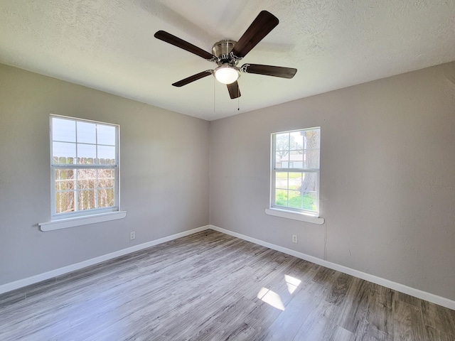 spare room featuring a textured ceiling, baseboards, a ceiling fan, and wood finished floors