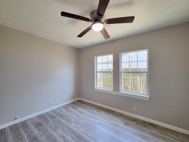 unfurnished room featuring baseboards, a textured ceiling, ceiling fan, and wood finished floors