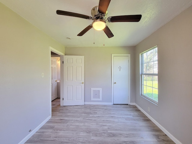 unfurnished bedroom with light wood-style floors, baseboards, and a ceiling fan