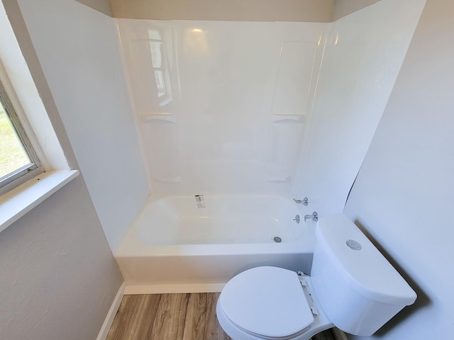 bathroom featuring toilet, baseboards, shower / bath combination, and wood finished floors