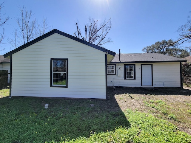 rear view of property with a lawn and fence
