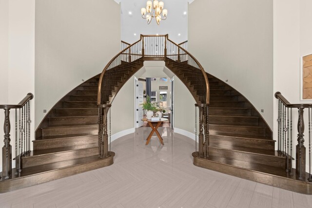 stairway with baseboards, a high ceiling, and a chandelier