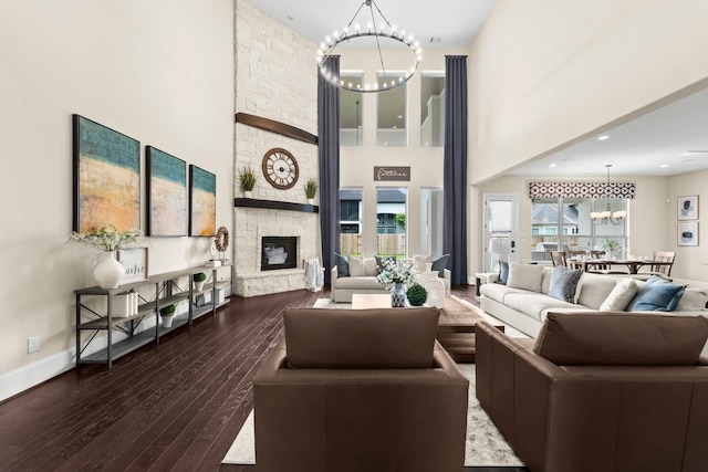 living room with a towering ceiling, hardwood / wood-style floors, a fireplace, baseboards, and a notable chandelier