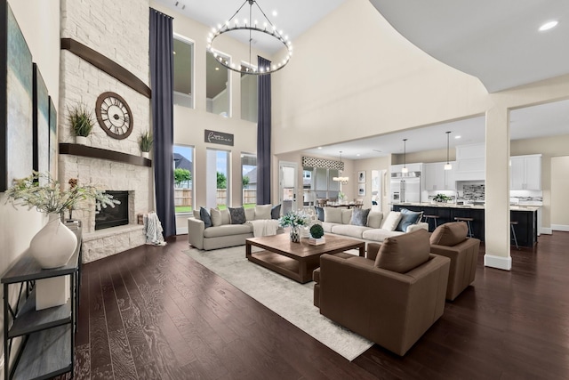 living area featuring a chandelier, dark wood finished floors, and a towering ceiling