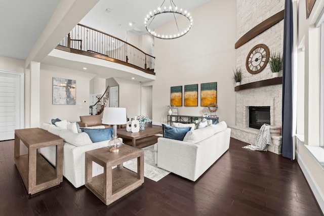 living area featuring a fireplace, a high ceiling, a notable chandelier, and hardwood / wood-style floors