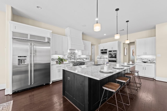 kitchen featuring white cabinetry, tasteful backsplash, a sink, dark wood finished floors, and appliances with stainless steel finishes
