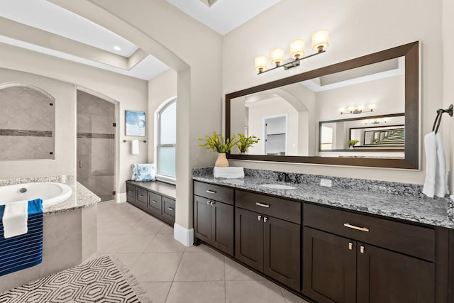 bathroom featuring tile patterned flooring, vanity, baseboards, a bath, and a tile shower