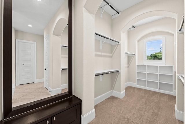 walk in closet featuring arched walkways and carpet flooring