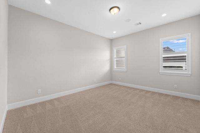 spare room featuring light colored carpet, baseboards, and plenty of natural light