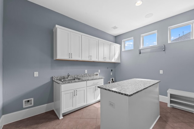 laundry room featuring baseboards, cabinet space, a sink, washer hookup, and light tile patterned floors