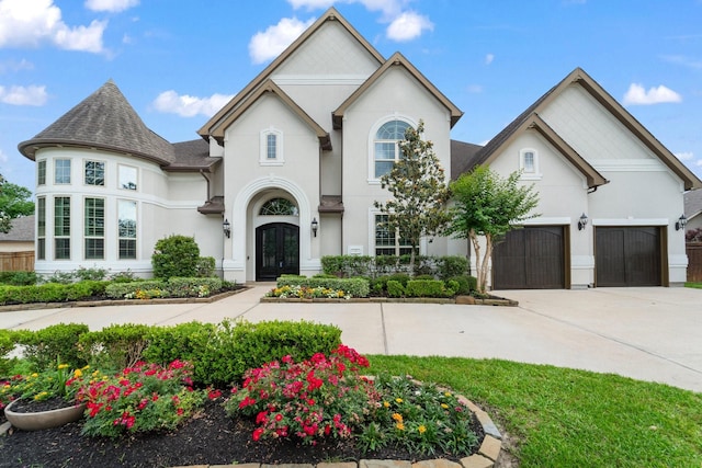 french country inspired facade featuring concrete driveway, an attached garage, french doors, and stucco siding