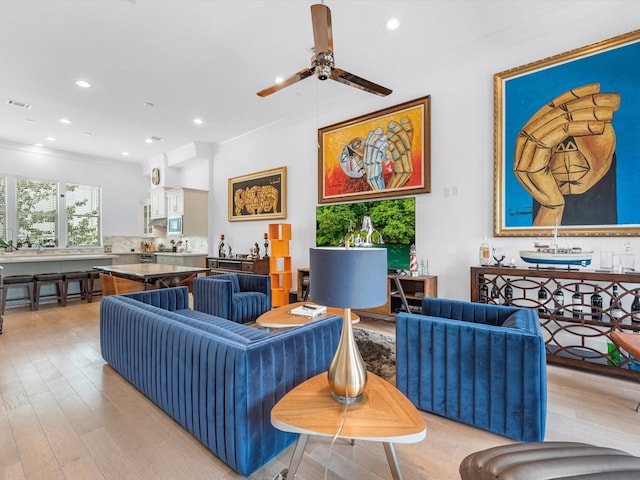 living room with ornamental molding, ceiling fan, light wood-type flooring, and recessed lighting