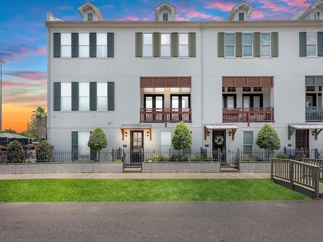 townhome / multi-family property with a fenced front yard and stucco siding