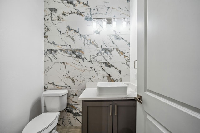 half bath featuring vanity, toilet, and tile walls