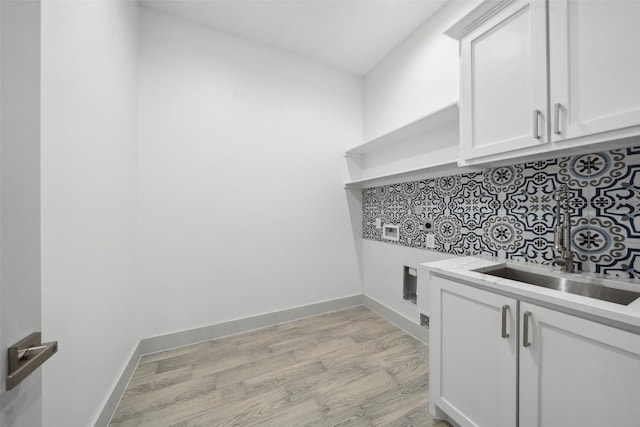 washroom with hookup for a washing machine, electric dryer hookup, a sink, cabinet space, and light wood finished floors