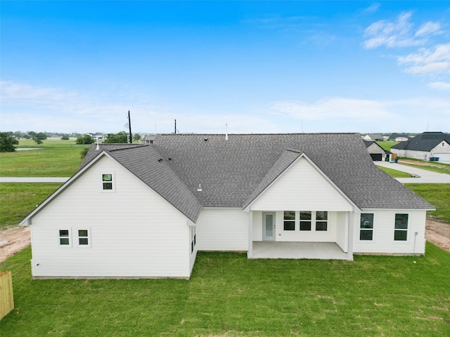 back of house featuring a shingled roof, a patio area, and a yard